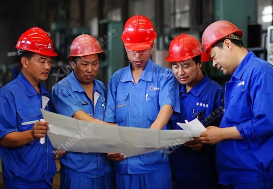 機(jī)械設(shè)備制造車間的工人正在根據(jù)設(shè)備圖紙分配任務(wù)。